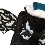 A close up view of the goth hot water bottle from the front, showing the details of the bats flying black and white fabric and the details of the soft luxury black velvet bottle cover. It shows the white towelling lining of the bottle cover.