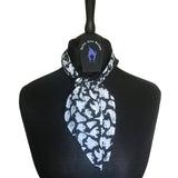 Lightweight cotton fabric scarf placed around a mannequins neck. Tied in a single loose knot around the neck with Nazine Alice Designs branded label. The fabric is an alternative gothic styled print of black background and white ghosts silhouettes.