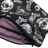 A close up of the skull, crow, spider, eyeball, coffin cosmetics bag which shows the zip and the lining inside the product which is a dark shade of purple. The zip is black, blends in, and is neatly hemmed.