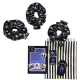 A gift set of three goth scrunchies in a Spiders fabric, it is a black background with white spiders all over as the pattern. This design is called 'Spiders'. The scrunchie has a luxury silk label with the brand name 'Nazine Alice Designs' on it.