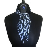 Lightweight cotton fabric scarf placed around a mannequins neck. Tied in a single loose knot around the neck with Nazine Alice Designs branded label. The fabric is an alternative gothic styled print of a black background with white bat silhouettes.